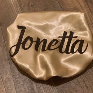 May include: A gold satin sleep cap with the name "Jonetta" written in black glitter.