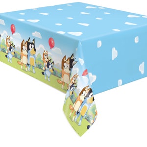 May include: Blue plastic tablecloth with a white cloud pattern and a repeating border of cartoon dogs with red balloons. The dogs are blue, brown, and orange.