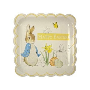 May include: A white paper square plate with scalloped edges features a cartoon illustration of Peter Rabbit in a blue jacket, holding a carrot. The plate also has a yellow banner with the text "Happy Easter" and a yellow daffodil flower. Two striped Easter eggs are in the bottom right corner.
