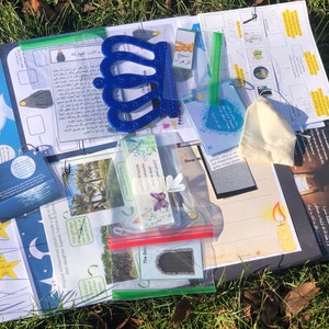 Puede incluir: Un conjunto de materiales educativos islámicos para niños, que incluye una corona azul, una bolsa blanca, un libro pequeño y varias hojas impresas con texto árabe e ilustraciones.