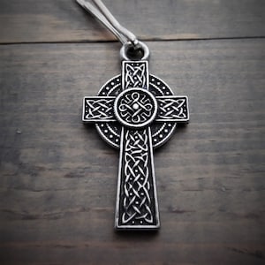 Puede incluir: Un tirador de cremallera de plata en forma de cruz celta con un intrincado diseño de nudos. La cruz tiene un centro circular con un diseño de nudos más pequeño.