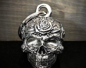 May include: Silver skull keychain with a detailed rose design. The skull has a detailed face with a rose on the forehead and roses around the jawline.
