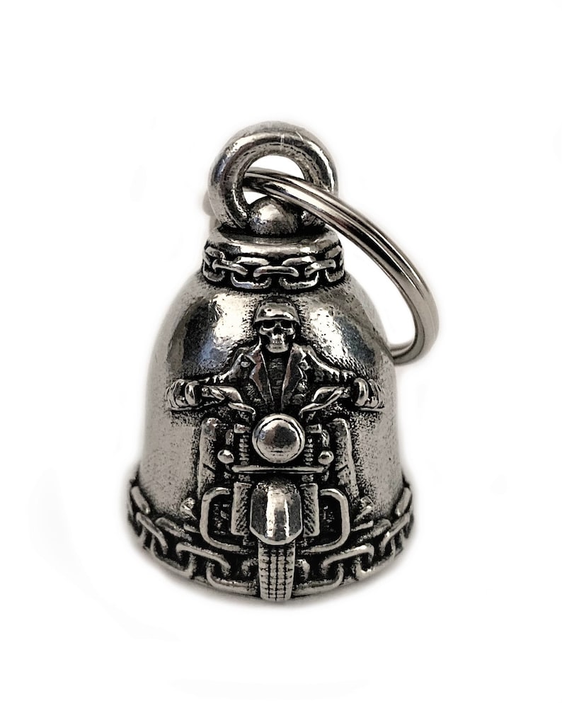 May include: Silver motorcycle bell keychain with a skull riding a motorcycle. The bell has a chain design around the top and bottom.