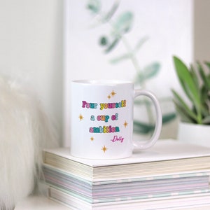 May include: White ceramic mug with a gold star design and the text "Pour yourself a cup of ambition - Dolly" in colorful letters.