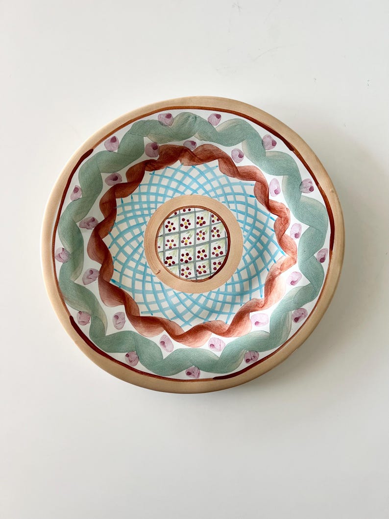 Pu&ograve; includere: Un set di tre tazze in ceramica con una glassa screziata color crema. Ogni tazza presenta un design dipinto a mano diverso: una foglia blu e verde, un fiore giallo e una bacca rossa. Le tazze hanno un design semplice e moderno.