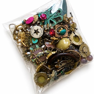 May include: A clear plastic bag filled with a collection of assorted costume jewelry, including gold-tone metal pieces, faux pearls, colorful beads, and a circular charm engraved with the text one wish good for.