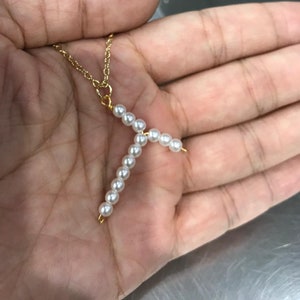 May include: A gold chain necklace with a pearl pendant in the shape of the letter Y.