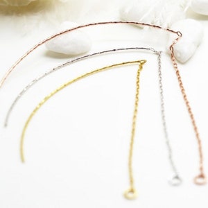 May include: Four different colored chain extenders, each with a small loop at the end. The chains are rose gold, silver, gold, and white gold.