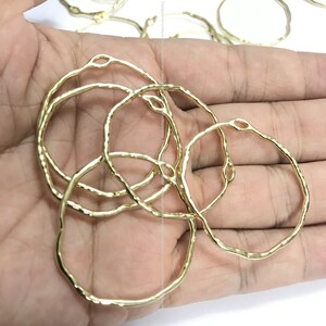 May include: A close-up of a pile of gold-coloured metal hoops. The hoops are all the same size and have a hammered texture.