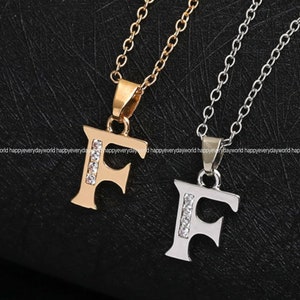May include: Two necklaces with letter F pendants. One necklace is gold with a gold letter F pendant with clear rhinestones. The other necklace is silver with a silver letter F pendant with clear rhinestones.