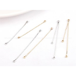 May include: Several delicate, silver and gold-colored jewelry chain connectors are arranged on a white surface. Each connector features a small loop at both ends and a textured, linear design. These components are ideal for jewelry making.