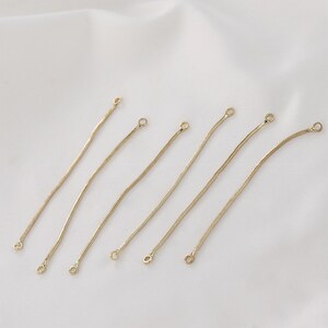 Può includere: Sei connettori per catena color oro con un design a catena a serpente. Ogni connettore ha un piccolo anello ad entrambe le estremità. I connettori sono disposti diagonalmente su uno sfondo bianco.