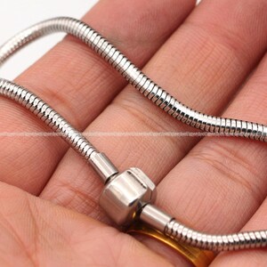 May include: A silver snake chain bracelet with a silver clasp.