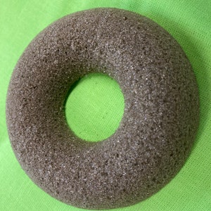 Könnte beinhalten: Ein braunes, donutförmiges Schaumstoffobjekt mit rauer Textur.