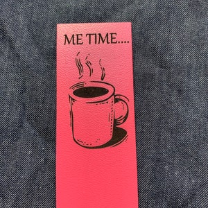 May include: Pink bookmark with the text "ME TIME..." and a black and white illustration of a coffee mug with steam rising from it.