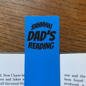 May include: A blue bookmark with the text "SHHHHH! DAD'S READING" in black.