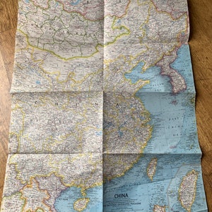 May include: A vintage map of China, printed by the National Geographic Magazine. The map shows the country's provinces, major cities, and geographical features. The map is folded and has a blue and yellow colour scheme.