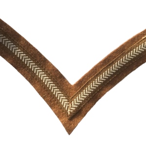 May include: A brown chevron-shaped patch with a white and gold chevron design.