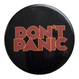May include: A black button with the words "DON'T PANIC" in red and yellow letters.