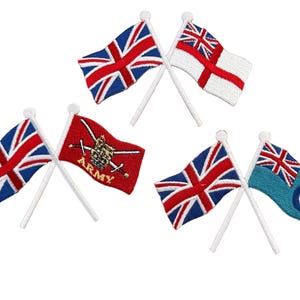 May include: Four pairs of small, crossed flags on white sticks. The flags are the Union Jack, the Royal Naval Ensign, the British Army flag, and the Royal Air Force roundel flag.