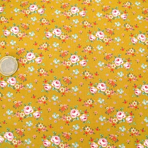 Könnte beinhalten: Ein senfgelber Stoff mit einem sich wiederholenden Muster aus kleinen rosa und weißen Rosen. Der Stoff ist mit einem dichten Muster aus winzigen Blumen bedeckt.