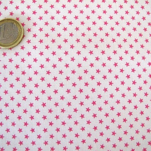 May include: Close-up of a white fabric patterned with small, evenly spaced, bright pink stars. A one Euro coin is in the upper left corner. The fabric is suitable for sewing, quilting, or craft projects.