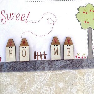 Könnte beinhalten: Holzbilder für die Dekoration, die "HOME" buchstabieren, mit einem roten Herzen auf jedem Haus. Die Häuser stehen auf einem weißen Hintergrund mit einer roten gepunkteten Linie und einem kleinen braunen Zaun.