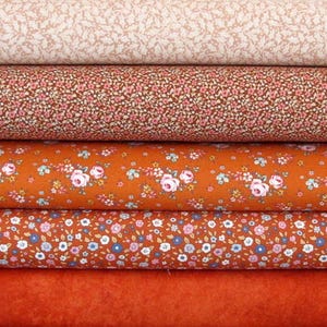 May include: Four rolls of fabric with different floral patterns. The top roll is a light beige with a small floral pattern. The second roll is a brown fabric with a small pink floral pattern. The third roll is a rust orange fabric with a larger floral pattern. The bottom roll is a solid rust orange fabric.