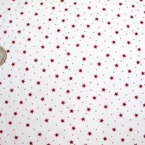 Op de afbeelding: Witte stof met een herhalend patroon van kleine rode sterren.