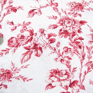 Könnte beinhalten: Weißer Stoff mit rotem Blumenmuster. Das Muster zeigt Rosen, Blätter und andere florale Elemente.