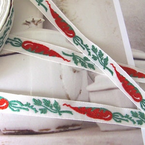 Può includere: Nastro bianco con un motivo ripetuto di carote rosse e fogliame verde. Il nastro è arrotolato e mostrato anche a strisce. Il design è in stile rustico e affascinante, adatto per lavori artigianali e decorazioni.