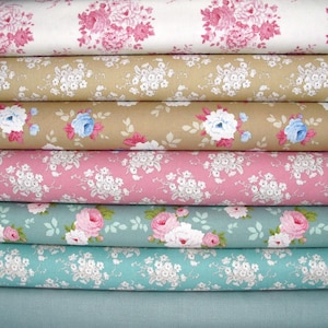 Pode incluir: Uma pilha de seis rolos de tecido com padrões florais. O rolo superior é branco com rosas cor-de-rosa, seguido de bege com flores brancas, bege com rosas azuis e cor-de-rosa, rosa com flores brancas, azul-petróleo com rosas cor-de-rosa e azul-petróleo com flores brancas.