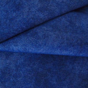 Könnte beinhalten: Nahaufnahme eines blauen Jeansstoffs mit einer strukturierten, leicht marmorierten Oberfläche. Der Stoff ist in der Mitte gefaltet und zeigt die weiche, gewebte Textur.