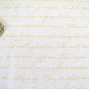 Könnte beinhalten: Nahaufnahme eines weißen Stoffes mit einem goldenen Schriftmuster. Der Stoff hat eine Leinenstruktur. Eine Euro-Münze ist in der linken unteren Ecke des Bildes zu sehen.