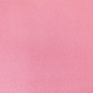 Könnte beinhalten: Ein einfarbiger rosa Stoff mit einer dezenten gewebten Textur.