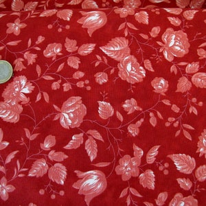 Könnte beinhalten: Roter Stoff mit weißem Blumenmuster. Der Stoff zeigt ein sich wiederholendes Muster aus kleinen weißen Blüten und Blättern auf rotem Hintergrund.