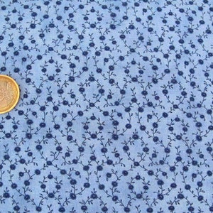 Op de afbeelding: Blauwe stof met een herhalend patroon van kleine donkerblauwe bloemen en wijnstokken.