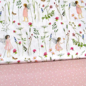 Könnte beinhalten: Weißer Stoff mit einem sich wiederholenden Muster aus rosa Blüten, grünen Blättern und Feen mit Flügeln. Der Stoff ist in der Mitte gefaltet und zeigt darunter einen rosa Stoff mit weißen Punkten.