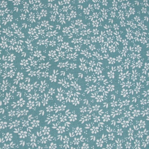 Op de afbeelding: Close-up van een turquoise stof met een herhalend patroon van kleine witte bloemen en bladeren. Het bloemmotief is dicht op het textiel verdeeld, waardoor een textuur ontstaat. De stof is waarschijnlijk katoen of een vergelijkbaar materiaal.