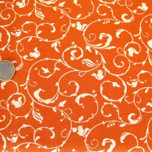 May include: Orange fabric with a white floral pattern. The pattern features swirling vines and leaves.