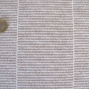 Könnte beinhalten: Nahaufnahme einer Euro-Münze auf einem weißen Stoffhintergrund mit einem sich wiederholenden Muster des Alphabets in Braun. Die Münze ist silberfarben und zeigt auf der einen Seite ein Kopfbild und auf der anderen Seite einen Baum.
