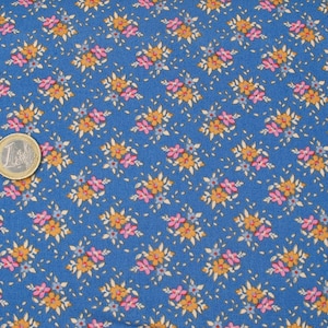 Könnte beinhalten: Ein blauer Stoff mit einem sich wiederholenden Muster aus kleinen rosa und orangefarbenen Blumen. Der Stoff hat eine subtile Textur.