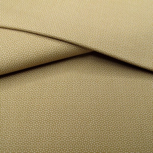 Könnte beinhalten: Ein gefaltetes Stück beigefarbener Stoff mit einem feinen, sich wiederholenden geometrischen Punktmuster. Das Textil weist ein gleichmäßiges Gewebe mit kleinen, hellen kreisförmigen Motiven auf, die gleichmäßig über die Oberfläche verteilt sind.