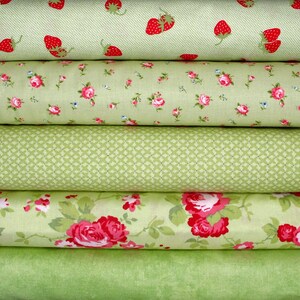 Può includere: Una pila di rotoli di tessuto in varie tonalità di verde. Il rotolo superiore presenta fragole rosse su sfondo verde chiaro. Altri rotoli mostrano motivi floreali e geometrici, tra cui rose rosa e una griglia a rombi. Il rotolo inferiore è verde chiaro.