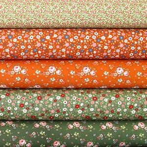 Könnte beinhalten: Vier Rollen Stoff mit kleinem Blumenmuster. Der Stoff ist in Grün-, Orange- und Weißtönen.