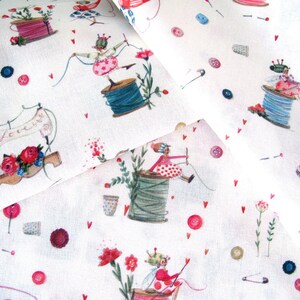 May include: White fabric with a whimsical sewing-themed print. The design features illustrations of sewing machines, spools of thread, buttons, and fairies. Red hearts and flowers add pops of color to the design.