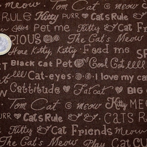 May include: Brown fabric with white text that says "meow", "Tom Cat", "Kitty", "Cat's Rule", "Pet me", "The Cat's Meow", "Play", "Here Kitty", "Feed me", "Spoil", "Perfect", "Black Cat", "Pet", "Cool Cat", "lll", "Pure", "ley cat", "lll", "Cat-eyes", "I love my cat", "Meow", "Cattitude", "Fat cat", "Big Cat", "Kitty Meow", "Cats Rule", "Cat Friends", "Meow", "The Cat's Meow", "Play", "Cat Curious".