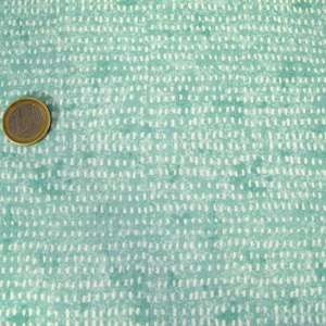 Può includere: Un primo piano di un tessuto color turchese con un motivo a pois bianchi. Il tessuto ha una texture sottile e un aspetto leggermente sbiadito.