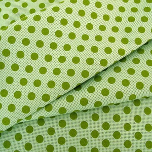 Op de afbeelding: Groene stof met een witte achtergrond en een herhalend patroon van groene stippen.