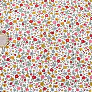May include: Close-up of a white fabric with a repeating pattern of tiny flowers in red, pink, yellow, and blue, with green leaves. A Euro coin is visible. The floral fabric is ideal for sewing and craft projects, offering a delicate and colourful design.